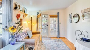 A cozy living room with a sofa, a coffee table, and a vase with flowers. There is a dining table with a bowl on it. - Walkable Studio w/ Patio in Tucson! (Tucson)