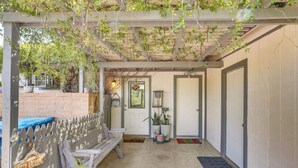 A covered patio with a wooden bench, potted plants, and a welcome mat. - Walkable Studio w/ Patio in Tucson! (Tucson)