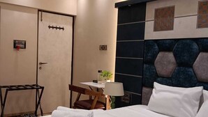 A hotel room with a bed, a desk, a chair, a lamp, and a wall-mounted headboard. - Luxurious Sea-view 3 BHK Service Apartment In CBD Belapur. Roy Bari, Satya Stays (Navi Mumbai)