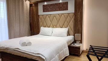 A neatly made bed with white linens, a headboard with a diamond pattern, and a bedside table with a lamp.