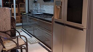 A modern kitchen with a stainless steel refrigerator, a gas stove, and a glass backsplash. - Luxurious Sea-view 3 BHK Service Apartment In CBD Belapur. Roy Bari, Satya Stays (Navi Mumbai)