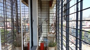 A narrow balcony with a wooden floor, metal railing, and potted plants. - Luxurious Sea-view 3 BHK Service Apartment In CBD Belapur. Roy Bari, Satya Stays (Navi Mumbai)