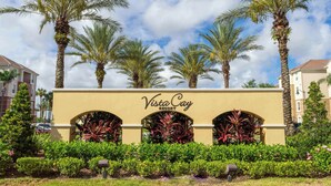 A sign for Vista Cay Resort with palm trees and greenery in the foreground.