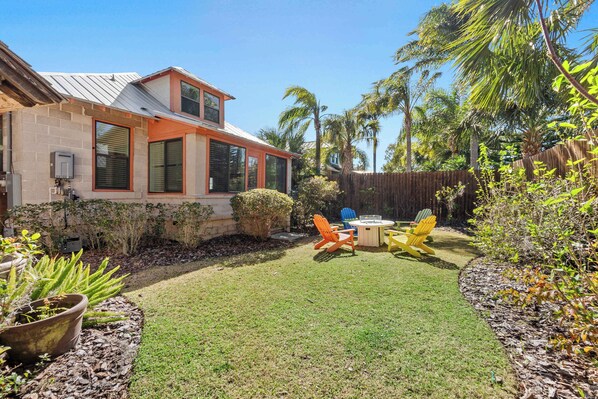 Una casa con patio, mobiliario exterior y jardín.