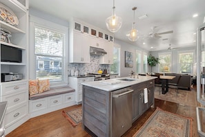 A modern kitchen with white cabinetry, a central island, and a dining area with a bench.