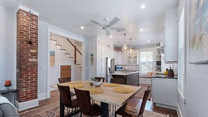 Une cuisine moderne avec un coin repas, un mur décoratif en briques et un ventilateur de plafond.
