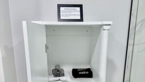 Une armoire blanche avec une inscription au-dessus, une cabine de douche en verre et une zone de douche carrelée en marbre.