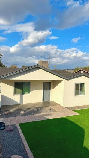 A single-story building with a flat roof, a front door, and a window.