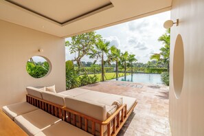 Quarto moderno com grande janela com vista para uma piscina e vegetação exuberante.