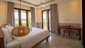 A bedroom with a bed, a desk, and a view of the outdoors. - Atelier Home by Great Bali Villas (Selemadeg)