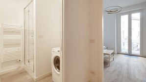 A laundry room with a washing machine, a glass door leading to a balcony, and a white interior. - GuestHost - Cozy apartment near Trotter Park (Milano)