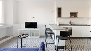 A modern kitchen with a TV, bar stools, and a dining area. - GuestHost - Cozy apartment near Trotter Park (Milano)