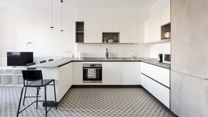 A modern kitchen with white cabinetry, a built-in oven, a black chair, and a patterned floor. - GuestHost - Cozy apartment near Trotter Park (Milano)