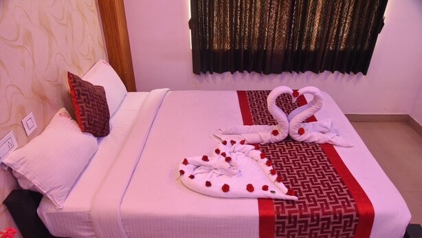 Un letto rifatto con cura, una coperta a motivi decorativi, un cuscino ornamentale e un’elegante composizione di asciugamani a forma di cigni con rose.