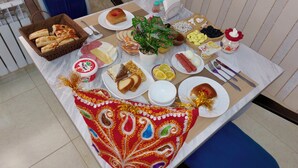 A dining table with various food items and a decorative cloth. - SHOM EAST HOTEL (Bukhara)