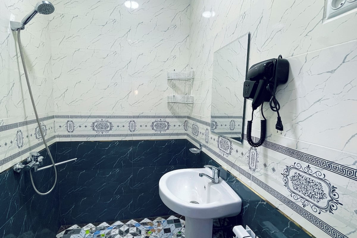 Un baño con lavamanos blanco, ducha y teléfono.