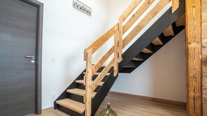 A staircase with wooden steps and black handrails, a door, and a bottle of corks on the floor.