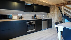 Eine moderne Küche mit schwarzen Schränken, Edelstahlgeräten und einer Holzbalkendecke.
