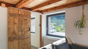 Ein Zimmer mit Holzboden, einer Schiebetür, einem Fenster mit Blick ins Grüne und einer hängenden Pflanze.