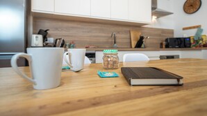 A kitchen with white cabinets, a wooden countertop, a coffee maker, a mug, a jar of snacks, and a book. - Le Perchoir, 6 people, Le gand valtin, full nature (Ban-sur-Meurthe-Clefcy)