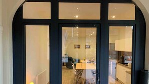 A modern interior with a dining area, kitchen, and living space visible through a glass door. - Le Perchoir, 6 people, Le gand valtin, full nature (Ban-sur-Meurthe-Clefcy)