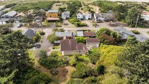 An aerial view of a coastal residential area with houses, a beach, and a road leading to the beach. - Charming Beach Hideaway w/ Fire Pit, Deck, & Close to Beach, Shops, Restaurants,and Sunset Views (Rockaway Beach)