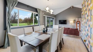 A modern dining area with a large table, chairs, and a view of the outdoors. - Incredible Golfside Single Level Ranch, Open Layout w/ Vintage Charm, Huge Patio, Close 2 Everything (Gresham)