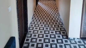 Un pasillo estrecho con baldosas de diseño, dos luces empotradas en la pared y una puerta a la izquierda.