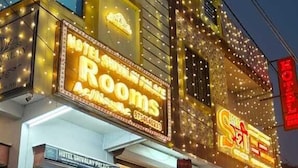 Un hotel con señalización iluminada, una motocicleta estacionada afuera y un escaparate con luces de colores.