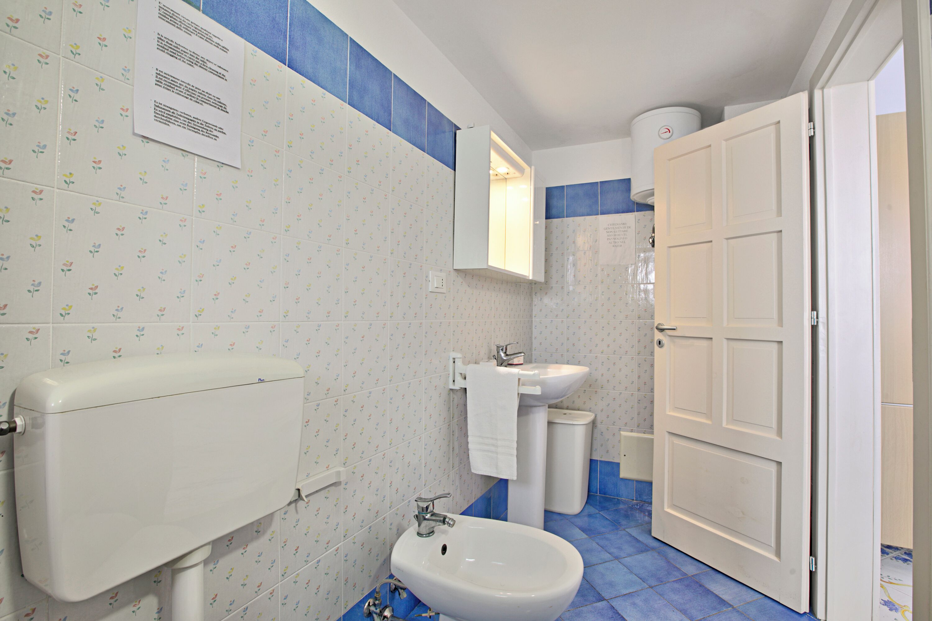 Un baño con inodoro, bidé, lavamanos y una puerta blanca.