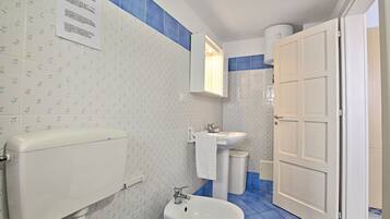 Un baño con inodoro, bidé, lavamanos y una puerta blanca.