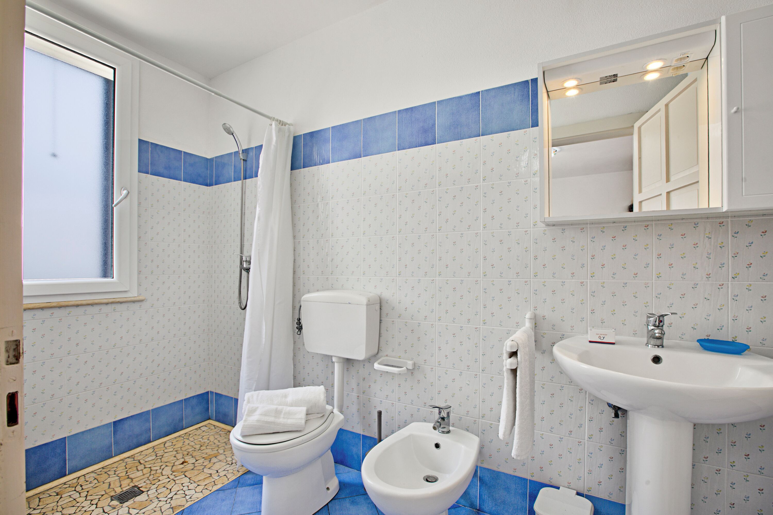 Une salle de bain équipée de toilettes, d’un bidet et d’un lavabo.