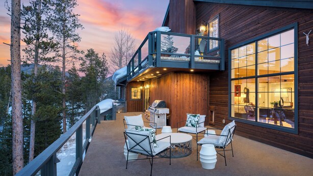 A wooden cabin with a balcony, outdoor seating, and a large window overlooking the interior. - Indoor Pool, Gym & Hot Tub Near Keystone | Crown Jewel of Keystone by AvantStay (Keystone)