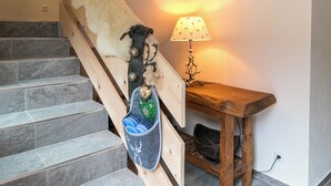 Un escalier avec une rampe en bois, une lampe fixée au mur et une petite table en bois sur laquelle se trouve une lampe.