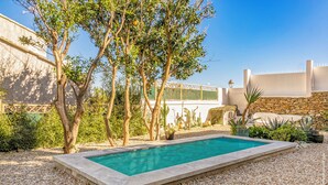 A rectangular swimming pool surrounded by pebbles, with trees and cacti in the background. - MARLI Exceptional Sea-View Villa with Private Pool – Authentic Cap Corse (Brando)