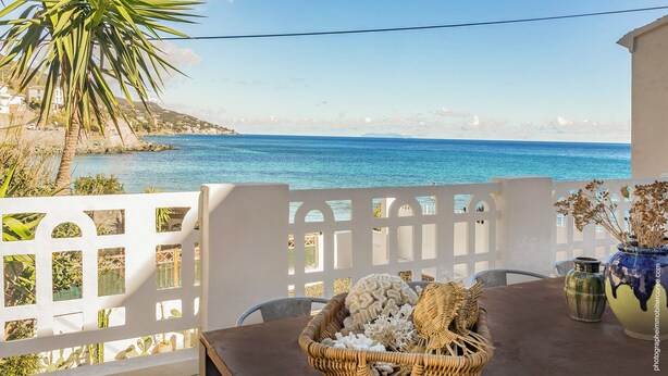 A balcony with a view of the sea, a wicker basket with decorative items, and a vase with dried flowers. - MARLI Exceptional Sea-View Villa with Private Pool – Authentic Cap Corse (Brando)