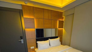 Een hotelkamer met een bed, een stoel, een kledingkast en een spiegel.
