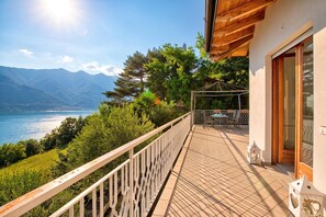 A balcony with a view of a lake and mountains, a wooden deck, and a glass door. - Casa Panorama in Tremosine With View Terrace (Tremosine)