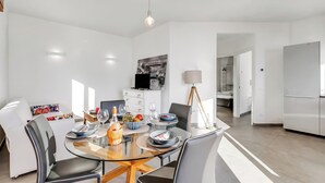 Un espace de salle à manger moderne avec une table en verre, des chaises et un luminaire suspendu.