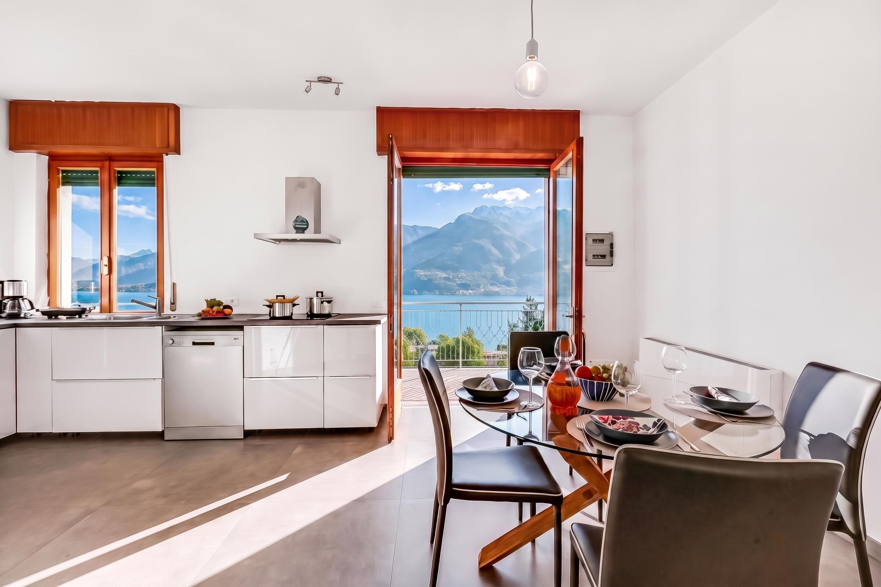 Eine moderne Küche mit Bergblick, ein Essbereich mit Tisch für zwei Personen und ein großes Fenster.