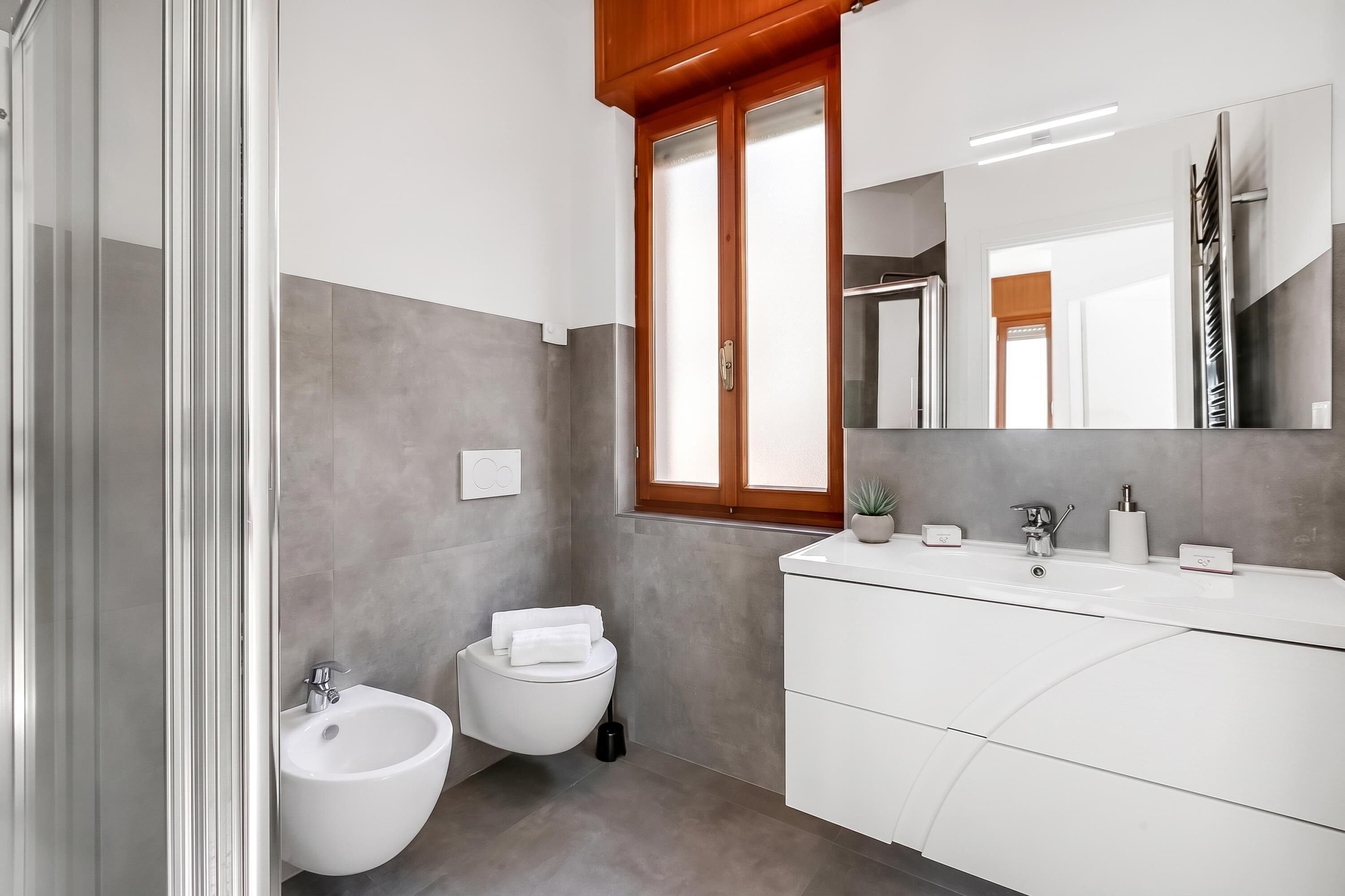 A modern bathroom with a bidet, a sink, and a large mirror.