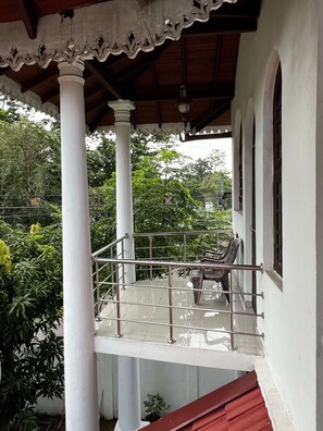 A covered balcony with a metal railing, white columns, and a red roof. - Villa Hirunika (Negombo)