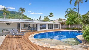 Ein modernes Haus mit Schwimmbad, Holzterrasse und überdachter Veranda.