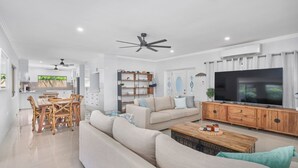 Ein modernes Wohnzimmer mit einer Couch, einem Couchtisch, einem Fernseher und einem Essbereich mit Stühlen und einem Tisch.