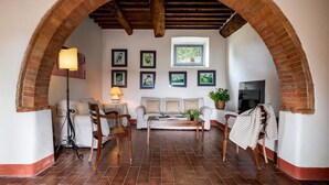 A cozy living room with a brick archway, a sofa set, a coffee table, and framed artwork on the wall. - In The Heart Of Chianti, Pool, Wifi, View (Lilliano)