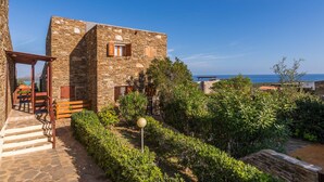 A stone building with a wooden porch and steps leading to a garden area. - Casa Lentischio in Stintino (Stintino)