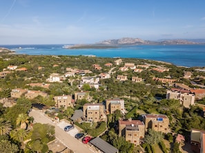 An aerial view of a coastal residential area with houses, a road, and a clear view of the sea and distant mountains. - Casa Lentischio in Stintino (Stintino)