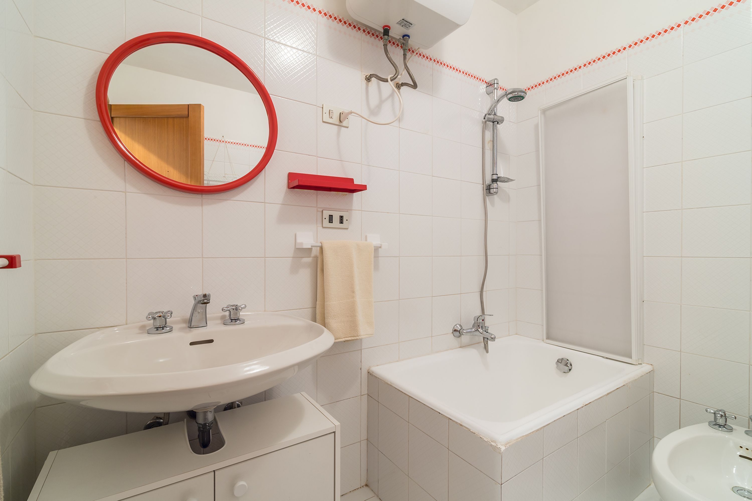 Une salle de bain équipée d’un lavabo, d’un miroir, d’une douche et de toilettes.