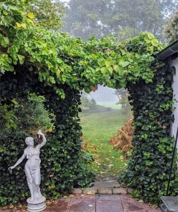 Stroll through the serene garden entrance, surrounded by lush greenery and a beautiful statue.