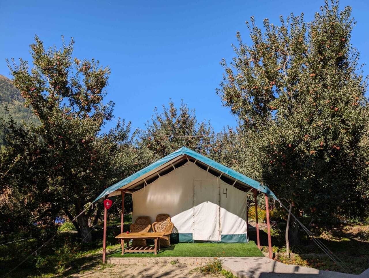 A small, single-room tent with a blue roof, a wooden bench, and a table.